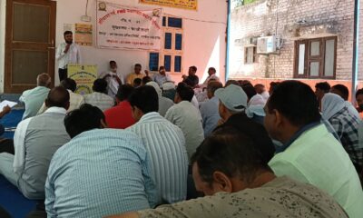 बैठक के दौरान मंच पर मौजूद पदाधिकारी और सामने बैठे कर्मचारी, समस्याओं को लेकर गंभीर चर्चा।